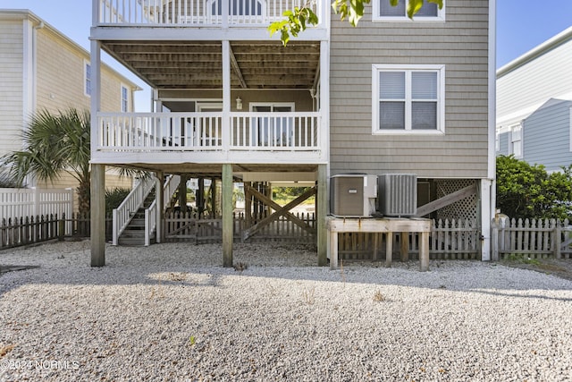 back of property featuring a deck, central AC unit, fence, stairs, and a carport