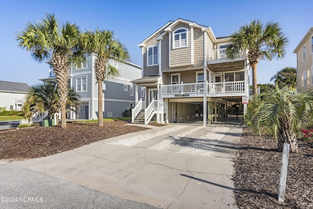 coastal home featuring a carport, concrete driveway, a porch, and a balcony