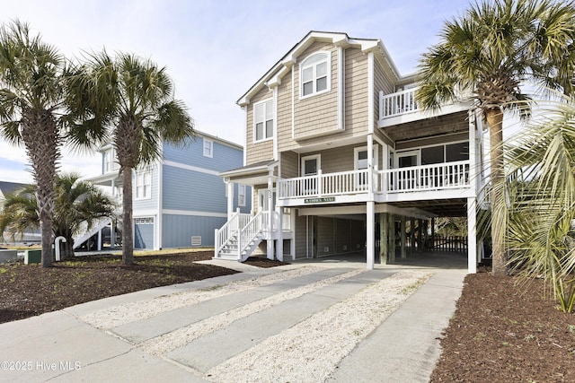 coastal home featuring driveway, a balcony, a porch, and a carport