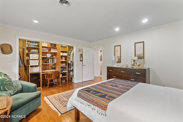 bedroom with crown molding, a closet, light wood-type flooring, and a walk in closet