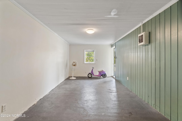 empty room with ornamental molding, wooden walls, and concrete flooring