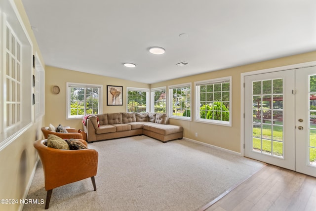 living room featuring lofted ceiling, french doors, and light hardwood / wood-style flooring