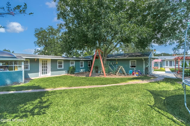 rear view of property with a lawn and a playground