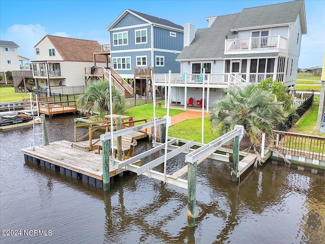 dock area featuring a balcony, a lawn, and a water view