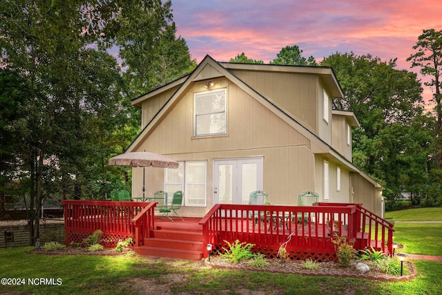 rear view of house featuring a wooden deck and a yard