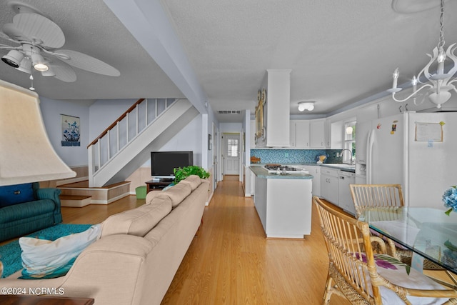 living area with a wealth of natural light, light wood finished floors, and stairs