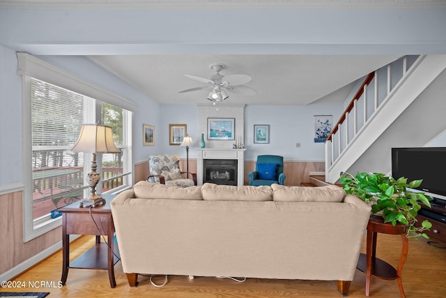 living area with light wood-type flooring, a fireplace, stairway, and a ceiling fan