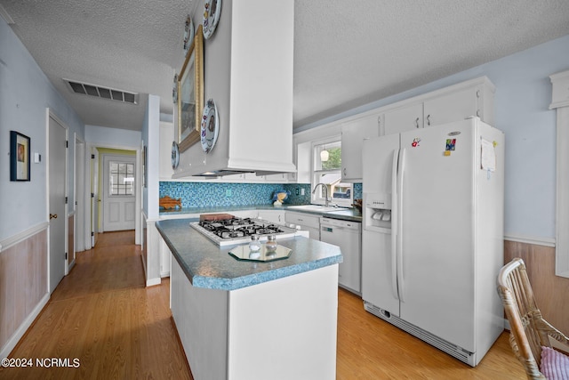 kitchen with white refrigerator with ice dispenser, visible vents, stainless steel gas stovetop, a sink, and dishwashing machine