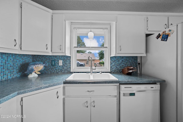 kitchen with decorative backsplash, dishwasher, dark countertops, white cabinetry, and a sink