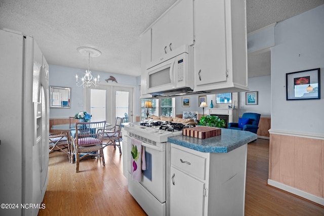 kitchen featuring white appliances, a wainscoted wall, a textured ceiling, and wood finished floors