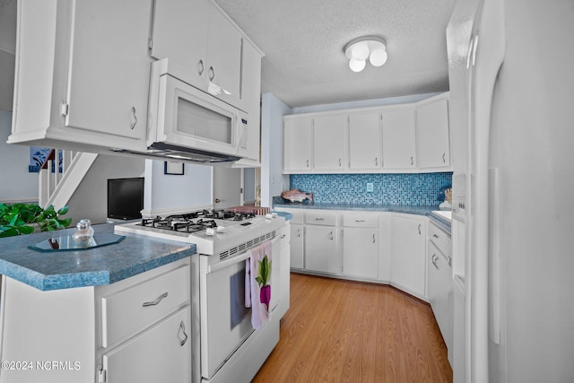 kitchen with light wood-style floors, white appliances, white cabinetry, and decorative backsplash