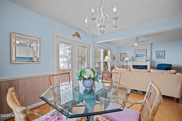 dining space featuring wainscoting, a fireplace, a textured ceiling, and wood finished floors