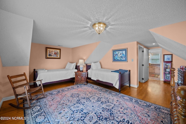 bedroom with a textured ceiling, baseboards, wood finished floors, and lofted ceiling