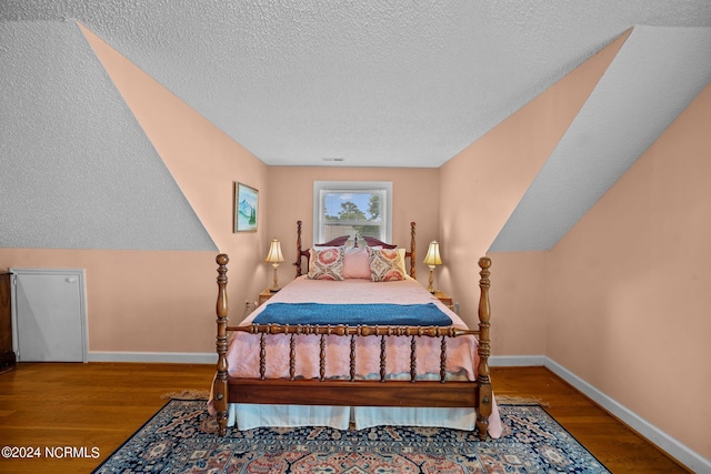 bedroom featuring a textured ceiling, wood finished floors, visible vents, and baseboards