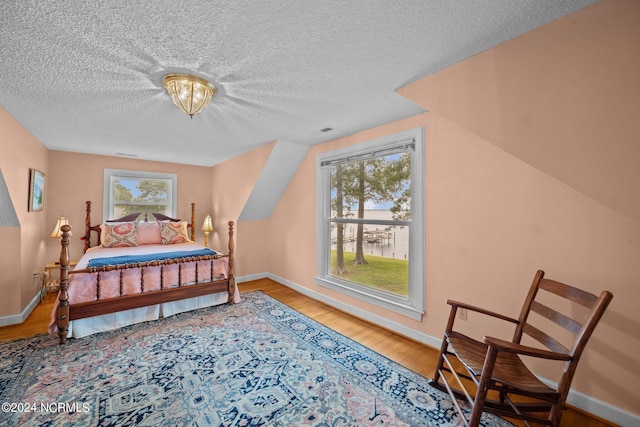 bedroom with lofted ceiling, visible vents, baseboards, and wood finished floors