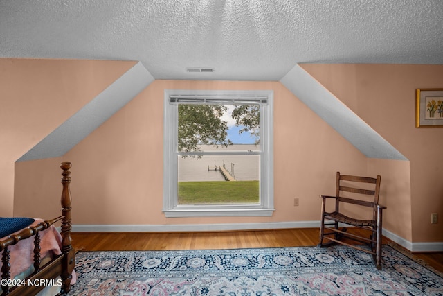 additional living space with lofted ceiling, wood finished floors, visible vents, and baseboards