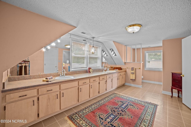 bathroom with double vanity, toilet, a sink, a textured ceiling, and tile patterned floors