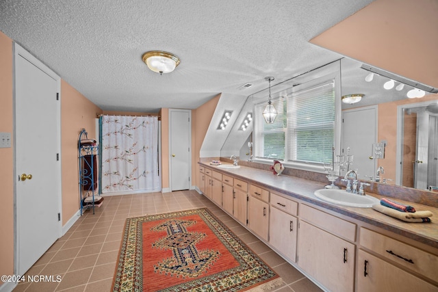 bathroom with a textured ceiling, a sink, and tile patterned floors