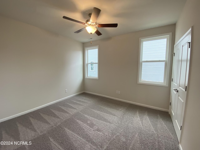 unfurnished room featuring dark carpet, baseboards, and ceiling fan