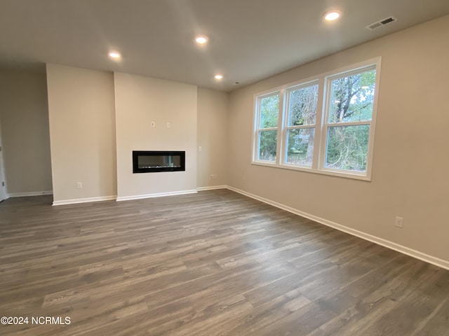 unfurnished living room with dark wood-style floors, a glass covered fireplace, visible vents, and recessed lighting