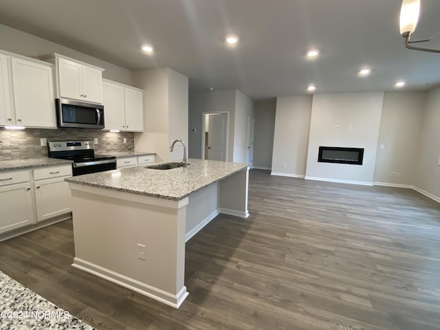 kitchen featuring decorative backsplash, an island with sink, dark wood-style flooring, stainless steel appliances, and a sink