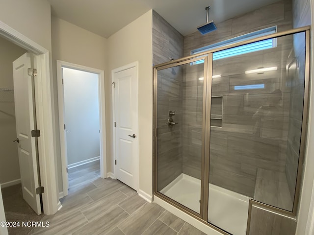 bathroom with a stall shower, wood finish floors, and baseboards