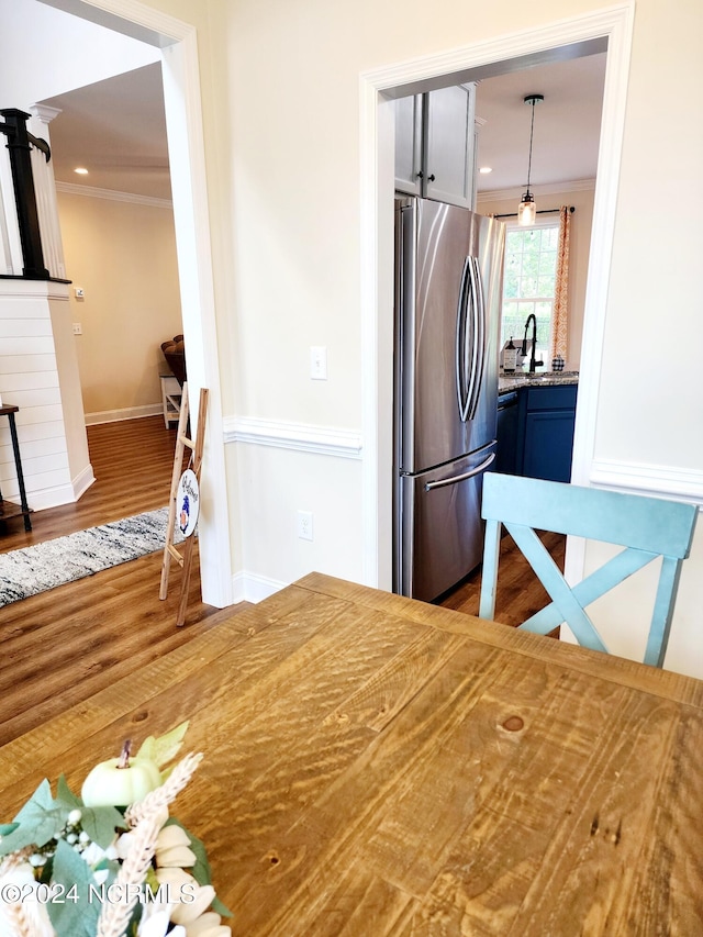 kitchen with sink, kitchen peninsula, stainless steel appliances, decorative light fixtures, and crown molding