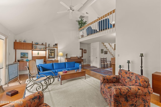 living room with ceiling fan, light hardwood / wood-style flooring, beam ceiling, and high vaulted ceiling