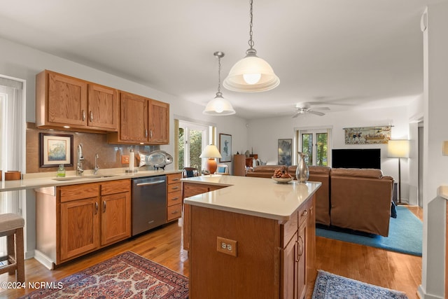 kitchen with hanging light fixtures, dishwasher, sink, and a healthy amount of sunlight