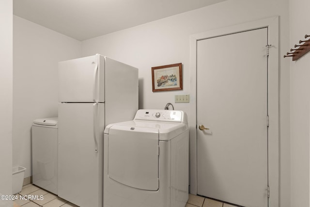 laundry area with separate washer and dryer and light tile patterned floors