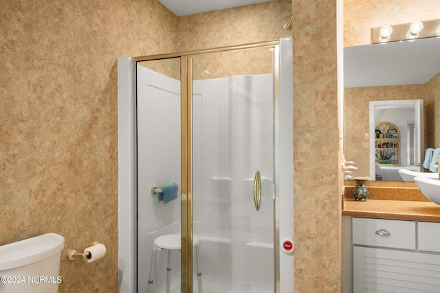 bathroom featuring vanity, toilet, and a shower with shower door