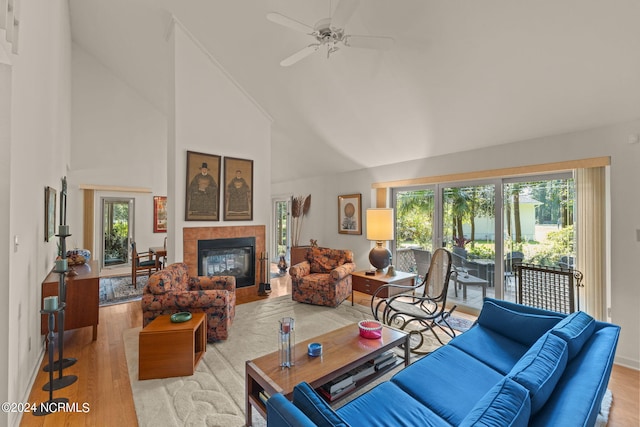 living room with ceiling fan, a fireplace, light hardwood / wood-style floors, and high vaulted ceiling