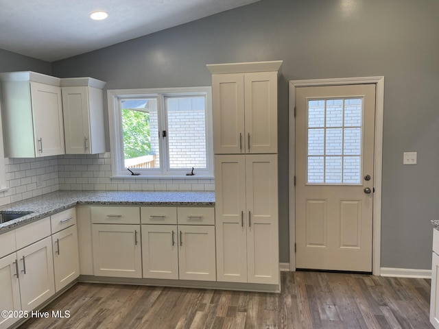 kitchen featuring dark wood-style flooring, tasteful backsplash, lofted ceiling, white cabinets, and light stone countertops