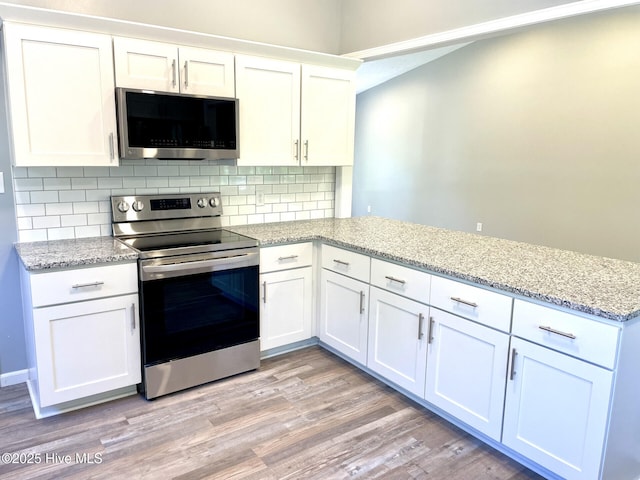 kitchen featuring stainless steel appliances, a peninsula, white cabinets, light wood-type flooring, and decorative backsplash