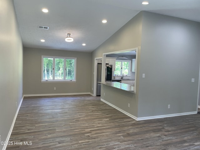 unfurnished living room featuring a sink, baseboards, visible vents, and dark wood-type flooring