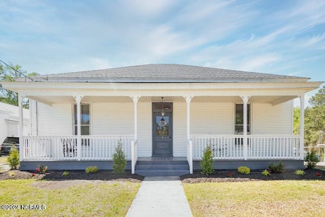 view of front of home featuring covered porch, roof with shingles, and a front lawn