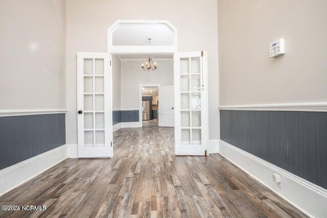 corridor featuring french doors, a chandelier, a high ceiling, and dark hardwood / wood-style floors