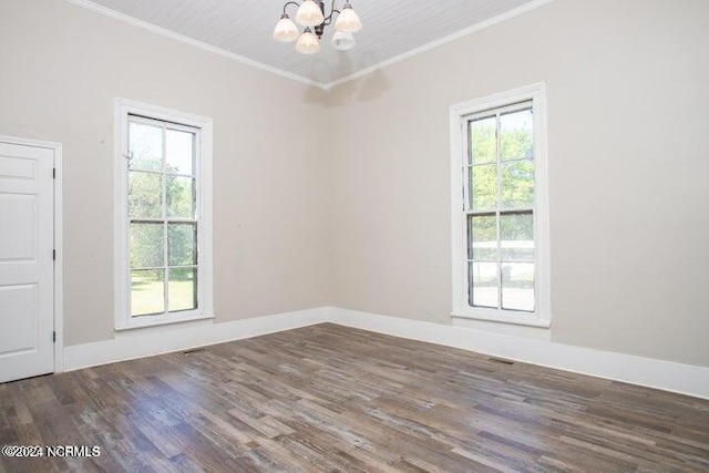 spare room featuring a chandelier, ornamental molding, wood finished floors, and baseboards