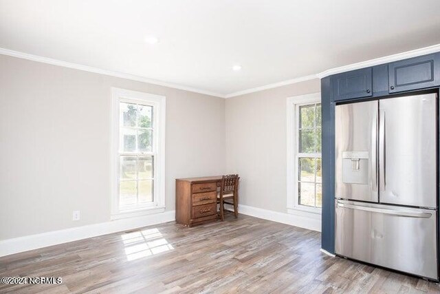 kitchen with light wood-type flooring, stainless steel fridge, crown molding, and a wealth of natural light