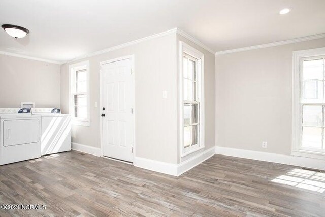 clothes washing area with wood-type flooring, plenty of natural light, ornamental molding, and washer and dryer