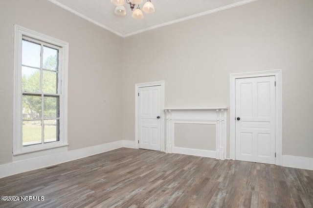 spare room featuring a chandelier, ornamental molding, wood finished floors, and baseboards