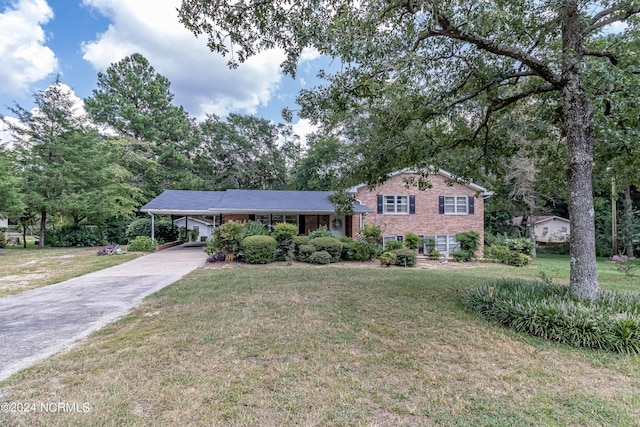 split level home with concrete driveway, a carport, a front yard, and brick siding