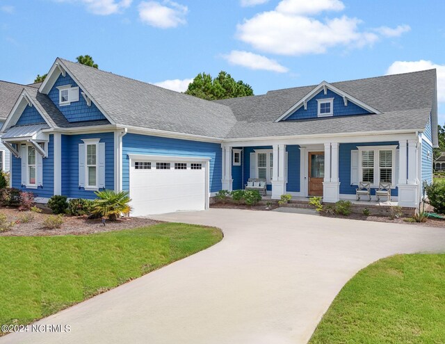 craftsman-style house featuring a garage, a front lawn, and covered porch