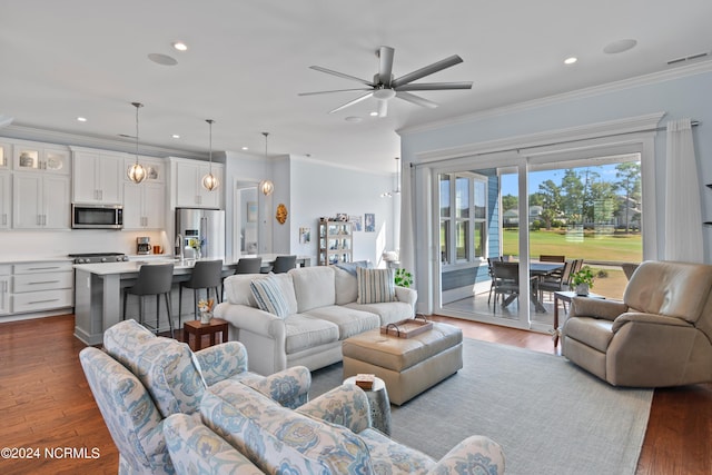 living area with dark wood-style floors, recessed lighting, visible vents, and ornamental molding