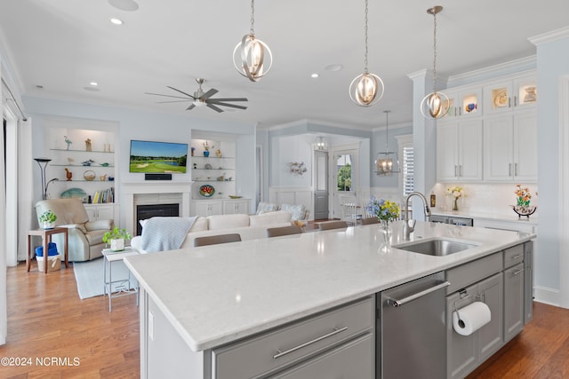 kitchen with open floor plan, crown molding, light wood-type flooring, a fireplace, and a sink