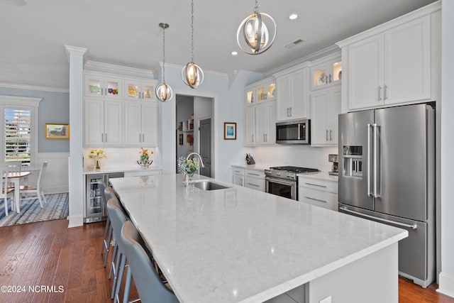 kitchen with premium appliances, wine cooler, a sink, visible vents, and ornamental molding