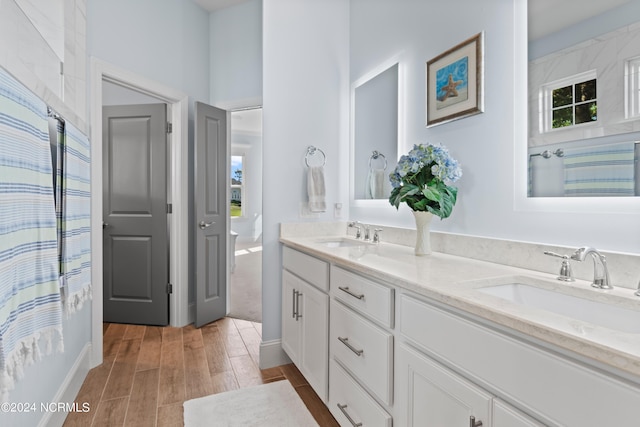 bathroom with double vanity, a sink, and wood finish floors