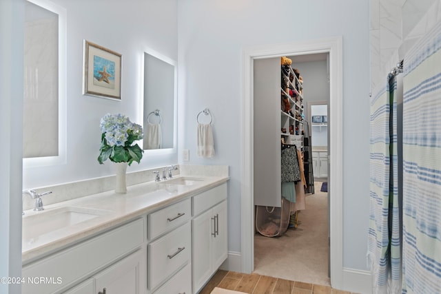 full bath with double vanity, a walk in closet, a sink, and a shower with shower curtain