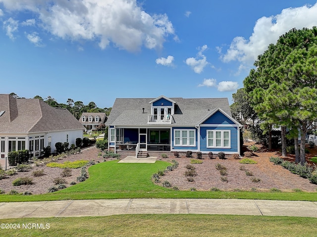 rear view of property featuring a sunroom, a yard, and a balcony