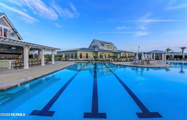 community pool with a patio, outdoor dry bar, and a pergola